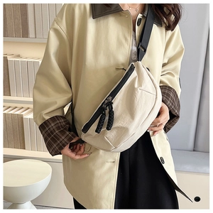 Detail of off-white crescent crossbody bag featuring durable black cord double zippers