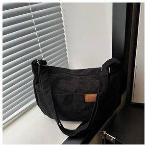 Detail of black corduroy shoulder bag showing fabric texture and FASHION leather label