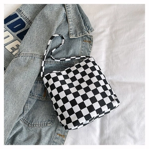 Gros plan d'un sac cabas en toile à damier noir et blanc sur une veste en jean
