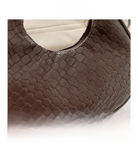 Detailed macro view of deep brown woven texture on a stylish crescent shoulder bag
