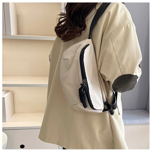 Detail view of beige nylon crossbody bag featuring heavy-duty black zippers and strap