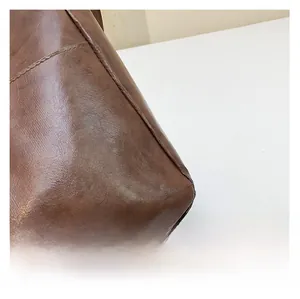 Detail of dark brown leather tote bag with glossy finish and neat stitching texture