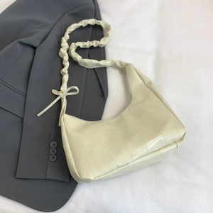 Detail of cream cloud bag showing geometric patchwork texture and ruffled strap with bow