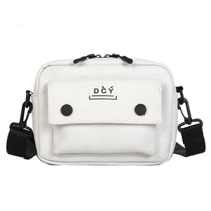 Detail view of white canvas crossbody bag with DCY logo and black adjustable strap