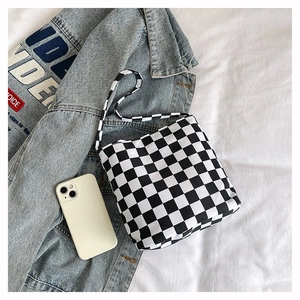 Détail du sac cabas en toile à damier noir et blanc posé sur une veste en jean bleu