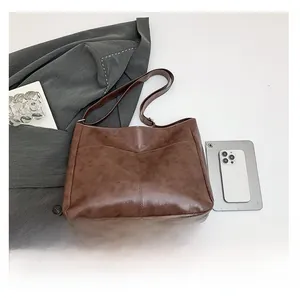 Brown vintage leather hobo bag shown next to a tablet for size comparison and scale