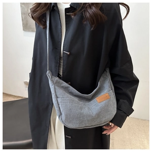 Detailed shot of the gray corduroy crossbody bag with adjustable strap on a female model