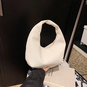 Chic cream white crescent hobo bag with woven texture pattern held by hand
