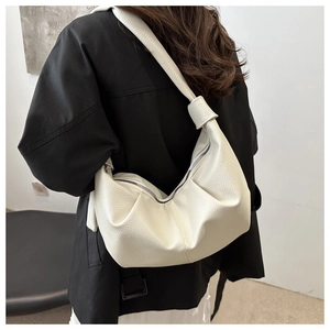 Detail of the white hobo bag showing litchi grain leather texture and pleated design