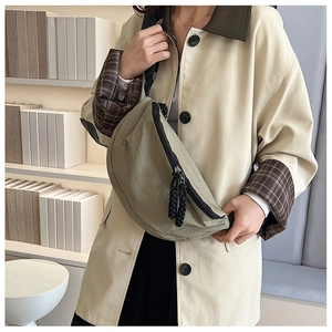Close-up of olive green crossbody bag with textured fabric and braided rope zipper pulls