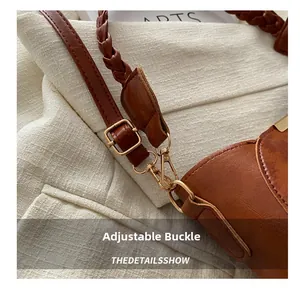 Détail de la boucle en métal doré ajustable et de la bandoulière tressée sur le sac marron