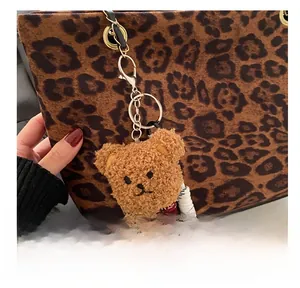 Détail d'un charm ours en peluche avec cordon tressé sur un sac à motif léopard