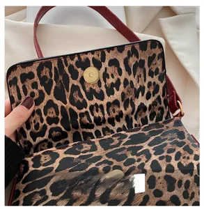 Close-up of golden metal magnetic buckle and burgundy strap on leopard print bag