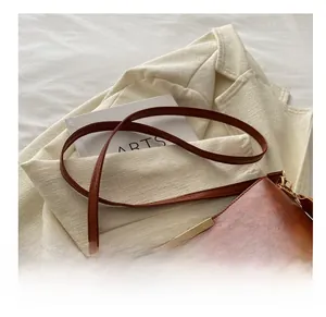 Détail du sac seau en cuir marron avec texture litchi et finitions métalliques dorées