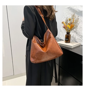 Brown oil-wax leather tote bag with irregular geometric folding shown on a shoulder