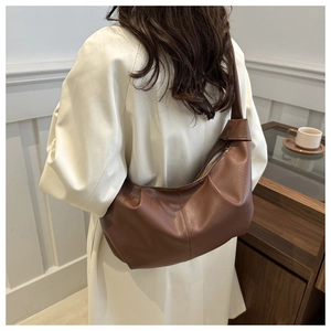 Detail view of large brown lychee leather shoulder bag on model showing size and drape