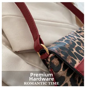 Detailed macro view of the red leather strap and golden D-ring hardware on a leopard bag