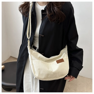 Close-up of beige corduroy crossbody bag texture and brown leather fashion label