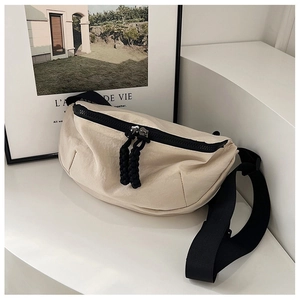 Detail of off-white nylon crossbody bag with dual black zippers and textured fabric