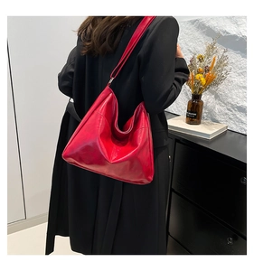 Detail view of large red glossy leather tote bag worn with a black office blazer