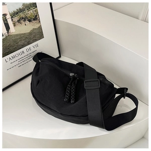 Close-up of black crescent nylon crossbody bag featuring woven zipper pulls and wide strap