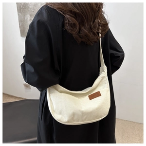 Back view of beige corduroy hobo bag on a model wearing black wool coat