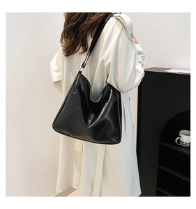 Minimalist black faux leather hobo bag worn by model showing large capacity and matte texture
