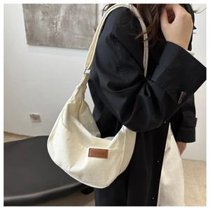 Detailed close-up of white corduroy shoulder bag with fashion leather tag and strap