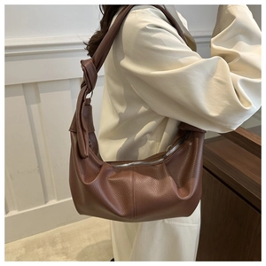 Detail of dark brown lychee leather texture and large knot design on the hobo bag strap
