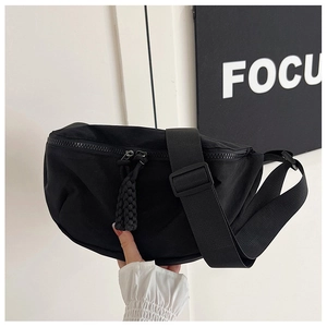 Close-up of black nylon crossbody bag featuring textured zippers and durable strap detail