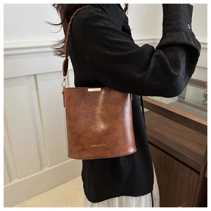 Sac seau marron en cuir texturé rétro avec une bandoulière tissée porté par un mannequin