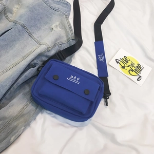 Detail view of the blue canvas crossbody bag with dual snap buttons and DCY brand logo