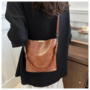 Détail d'un sac seau vintage marron avec poignée tressée et finitions en métal doré
