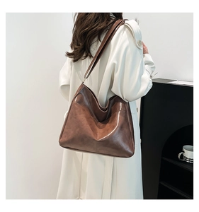 Detail of a large vintage brown leather tote bag with vertical stitching and wide strap