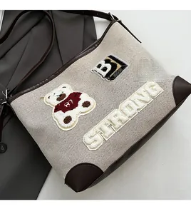 Detail view of canvas tote bag showing strong embroidery and brown leather edging finish