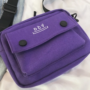 Close-up of purple canvas crossbody bag featuring DCY logo and black button details