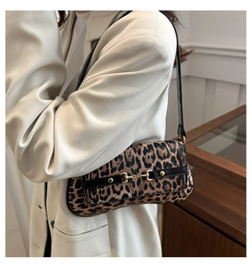 Close-up of leopard print baguette bag with golden horsebit detail on a model