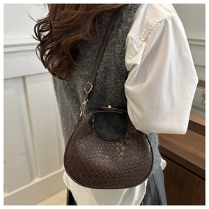 Brown woven crescent bag worn by model, showing the texture and adjustable shoulder strap