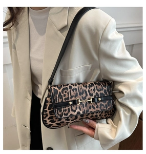 Detail of leopard print shoulder bag with gold horsebit hardware on a beige suit