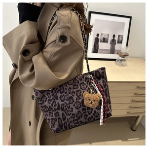 Détail d'un sac cabas léopard avec bandoulière en chaîne et pendentif ours mignon