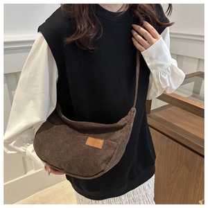 Detail of dark brown corduroy texture and fashion leather patch on a crescent crossbody bag