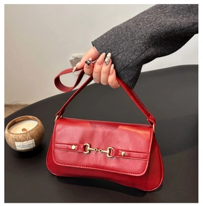 Detailed view of the red underarm bag featuring a classic gold horsebit metal buckle