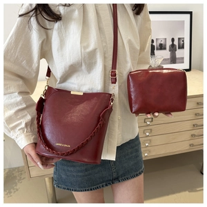 Détail du sac seau en cuir bordeaux avec anse tressée et mini pochette assortie