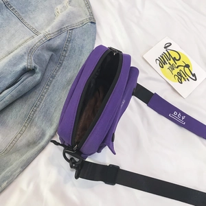 Detailed top view of purple canvas crossbody bag with adjustable black strap and inner lining