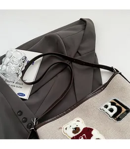 Detailed close-up of beige canvas tote bag featuring a cute plush bear embroidery detail