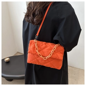 Détail du sac à bandoulière matelassé orange avec chaîne épaisse et motif losanges