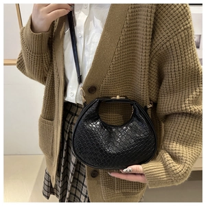 Detail shot of black crescent shoulder bag featuring woven texture and gold metal lock