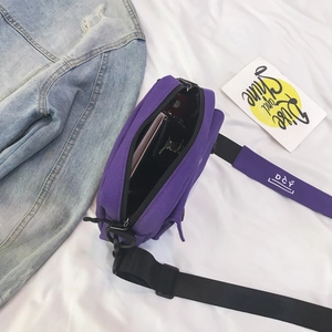 Detail view of purple canvas crossbody bag showing inner storage and logo shoulder strap