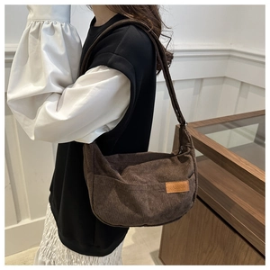 Detail of dark brown corduroy half-moon shoulder bag with leather fashion patch