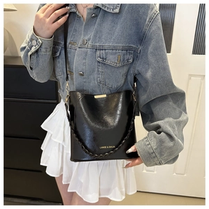 Sac seau en cuir noir porté avec détails dorés et poignée tissée pour femme